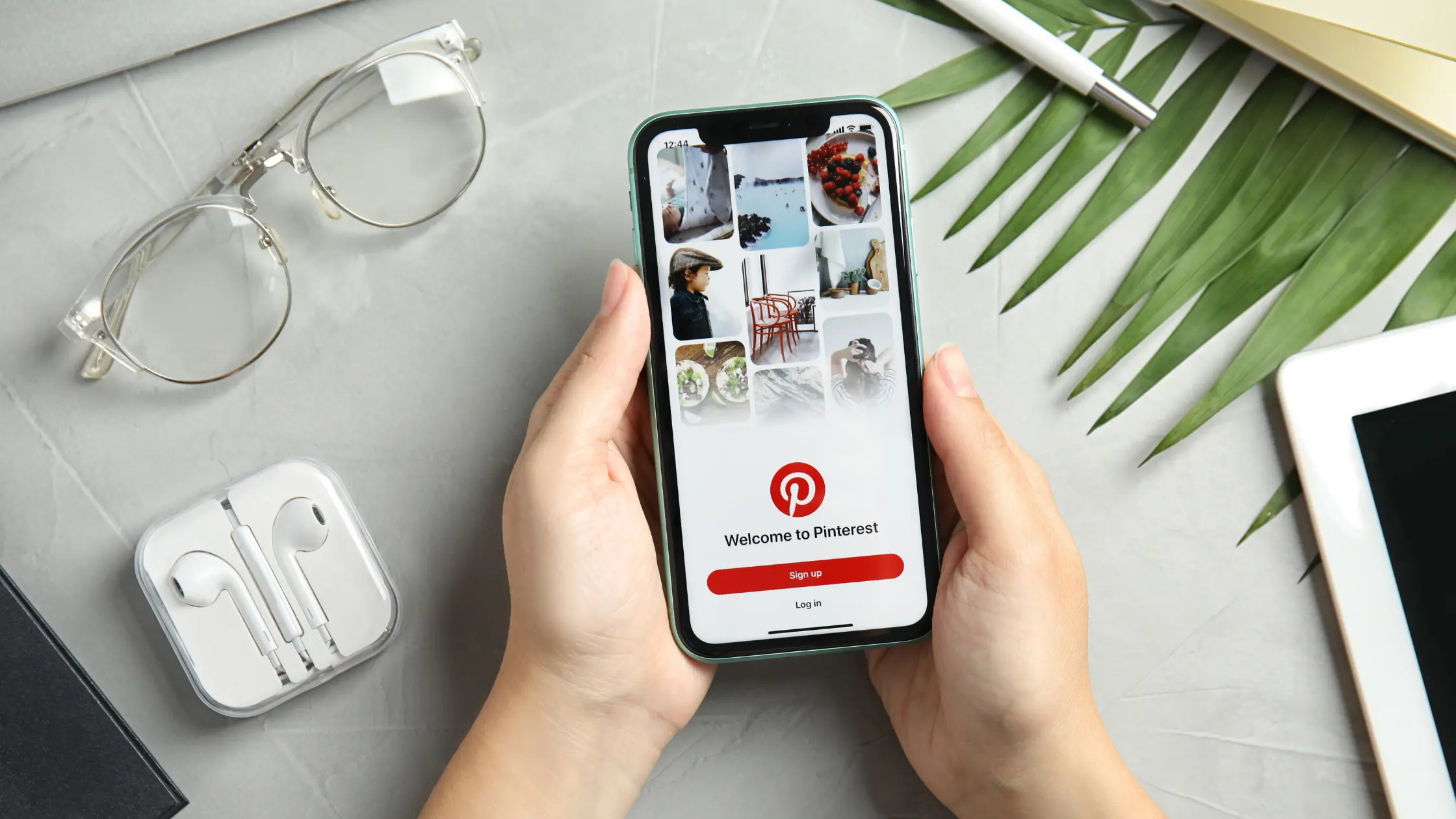 closeup of someone holding phone that's displaying a pinterest profile. the phone is above a table